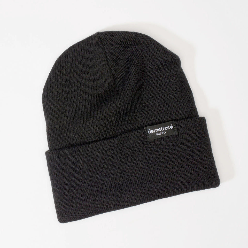 Solid black cuffed knit beanie with a black woven label.